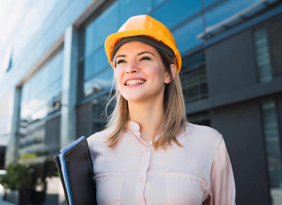 Insurance By Industry - Portrait of a Smiling Professional Engineer Standing Outdoors in Front of Building